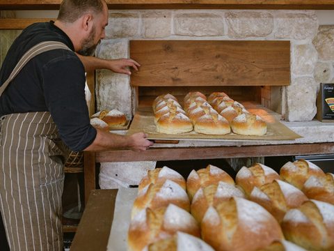 Bakker haalt vers brood uit de oven.