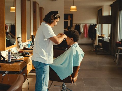 Kapper knipt een klant in een warm salon.