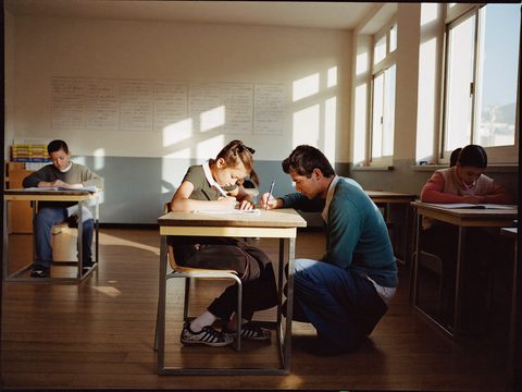 Leerkracht helpt een leerling in de klas.